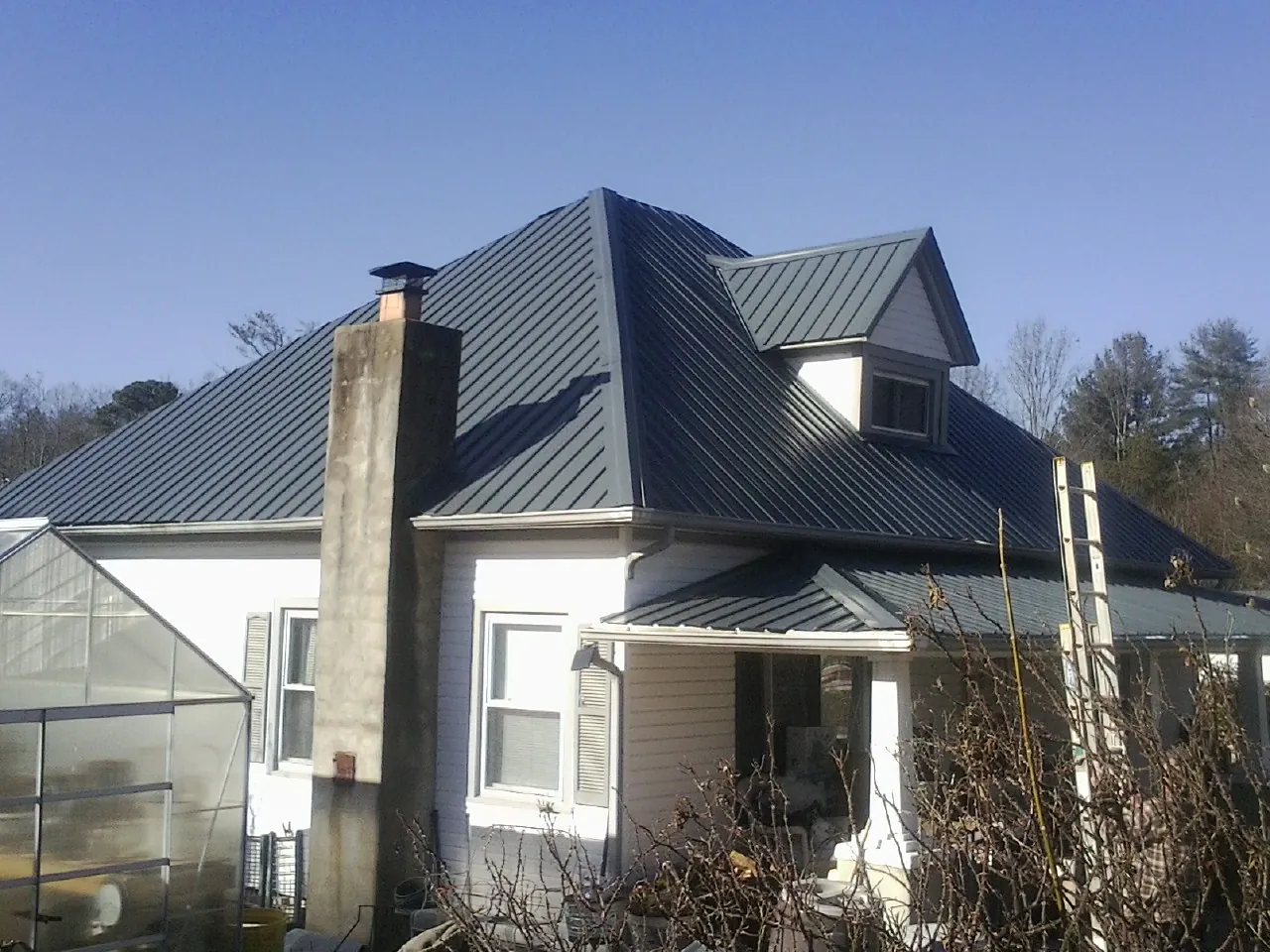 Dark blue standing seam metal roof on a white farmhouse with dormer — Slate & Tile Roof Repair by Roofing Brothers in Seven Valleys