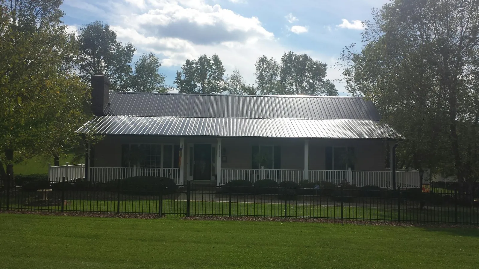 Gray metal roof on a brick ranch with a full width front porch — Gutter Guard Installation work by our crew in Seven Valleys