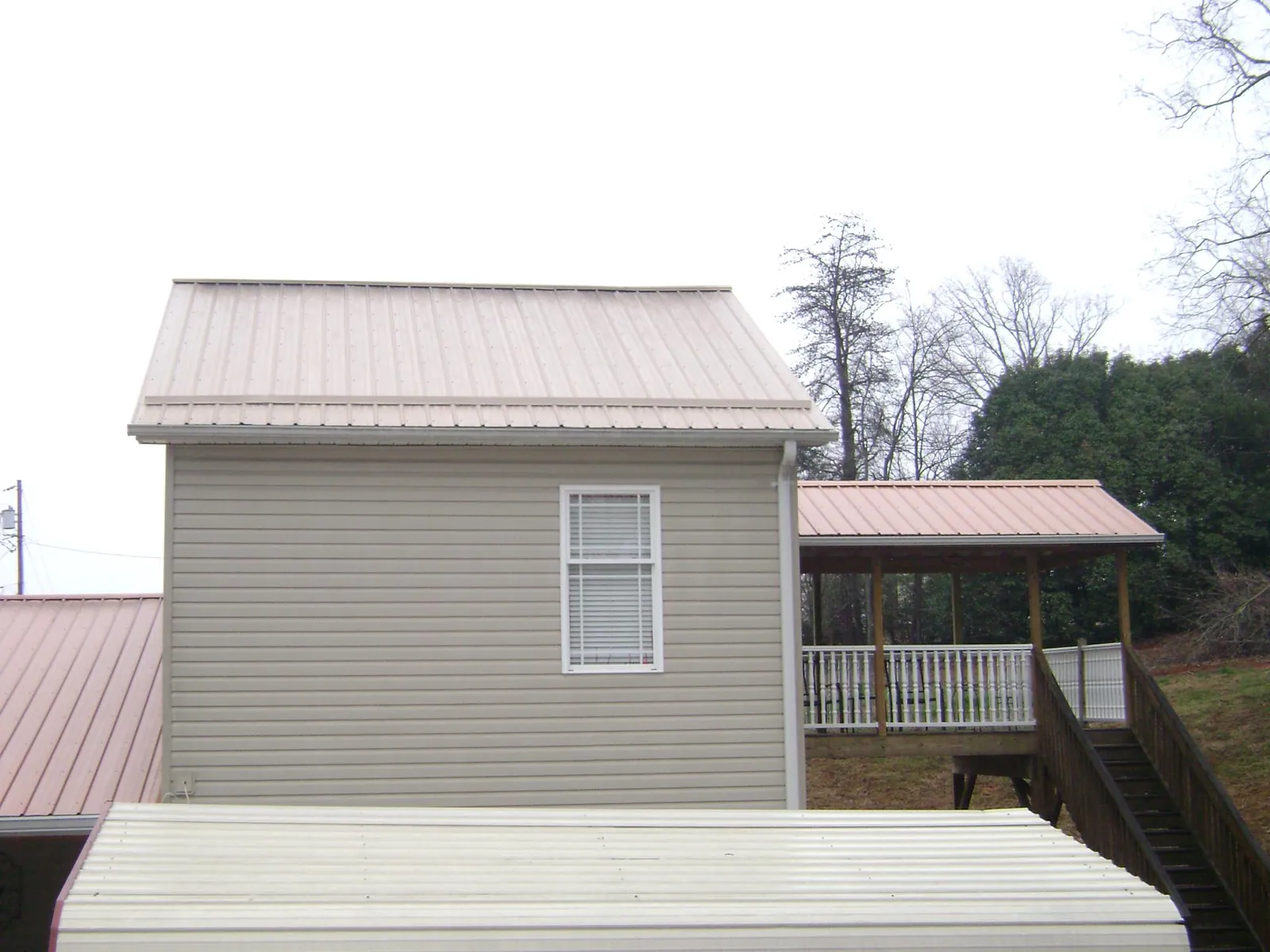 Tan metal roofs on a two story addition and attached porch, from a Roof Replacement job in Seven Valleys