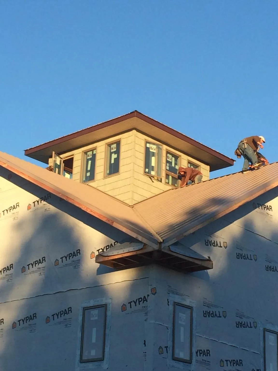Roofers working around a rooftop cupola on a new metal roof at sunset — Roof Waterproofing in Seven Valleys by Roofing Brothers
